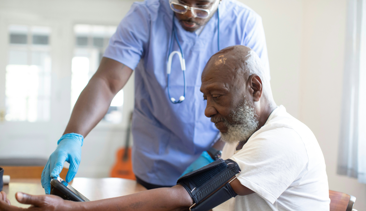 Older man getting blood pressure checked with a nurse assisting him