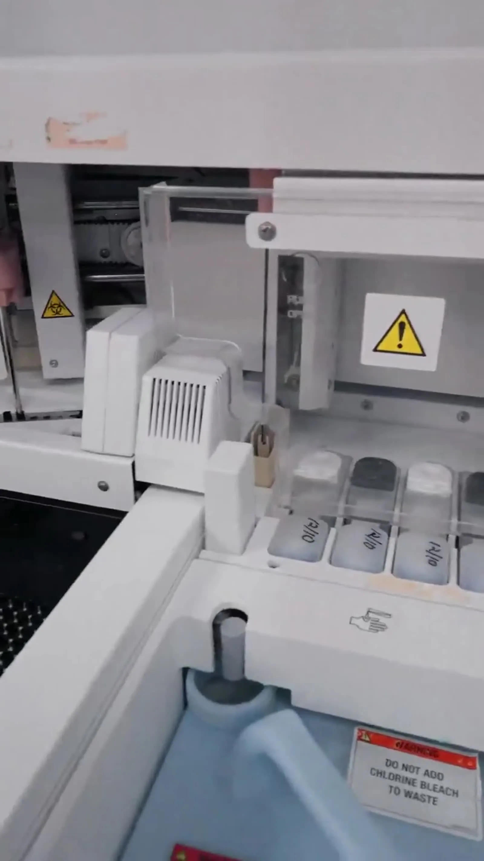 Laboratory analyzer with sample trays and safety labels.