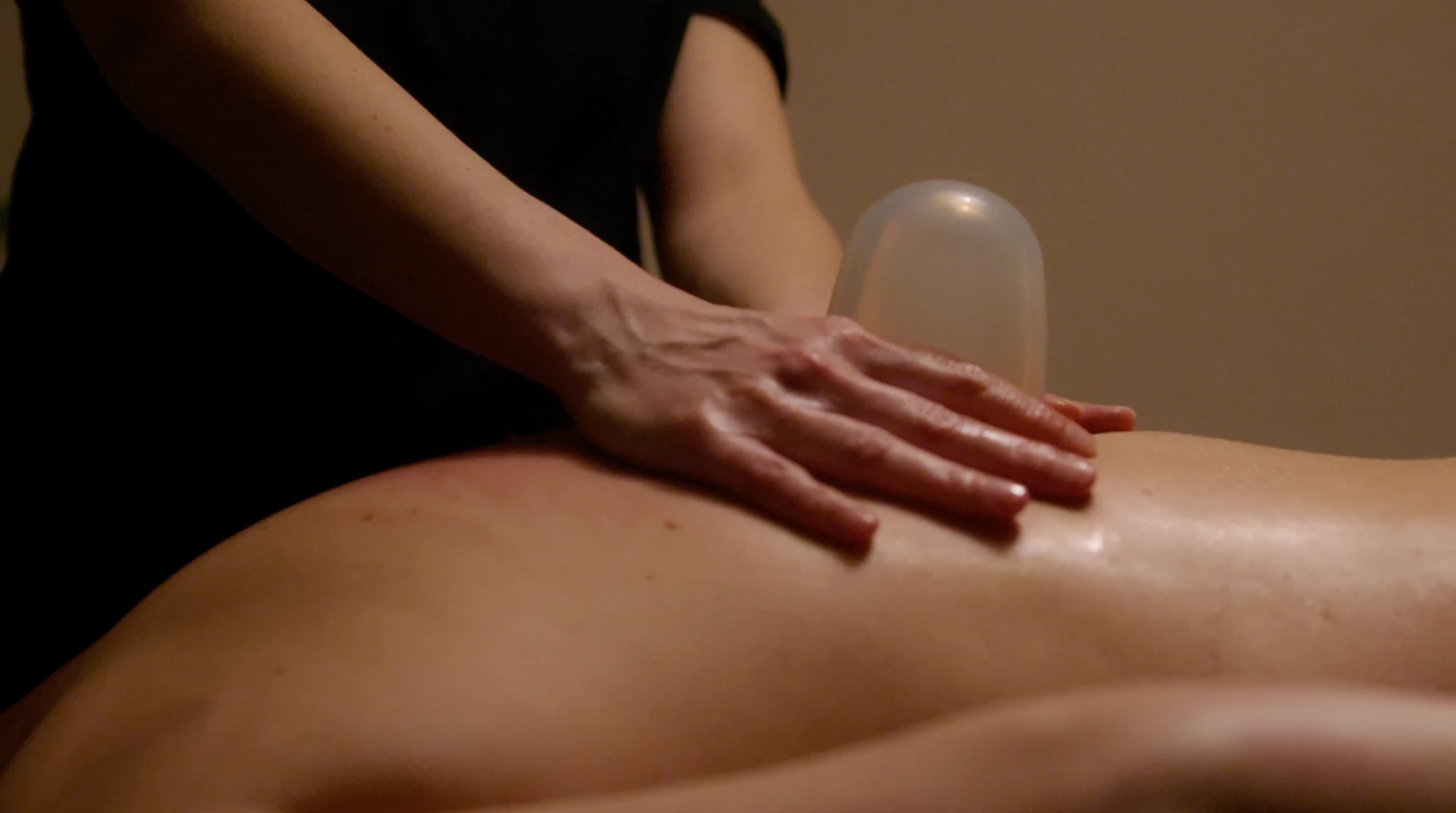 Cupping massage at Studio Release: a therapist's hand on a client's back beside a silicone cup