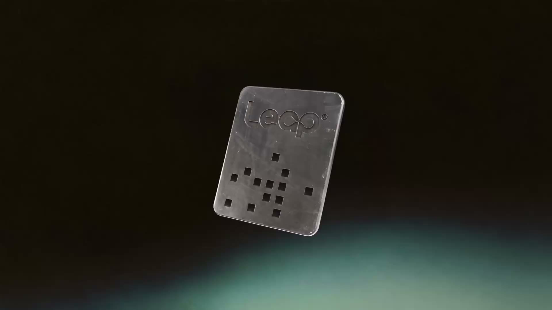The LEAP keychain tag in brushed metal, slowly turning