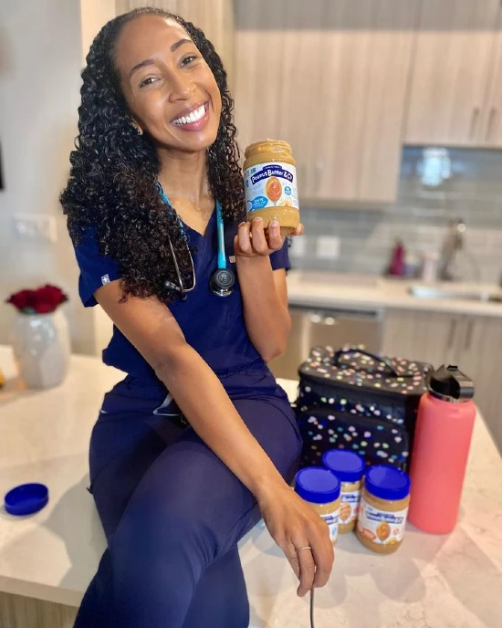 Victoria Humphrey sitting on the kitchen counter holding a jar of peanut butter
