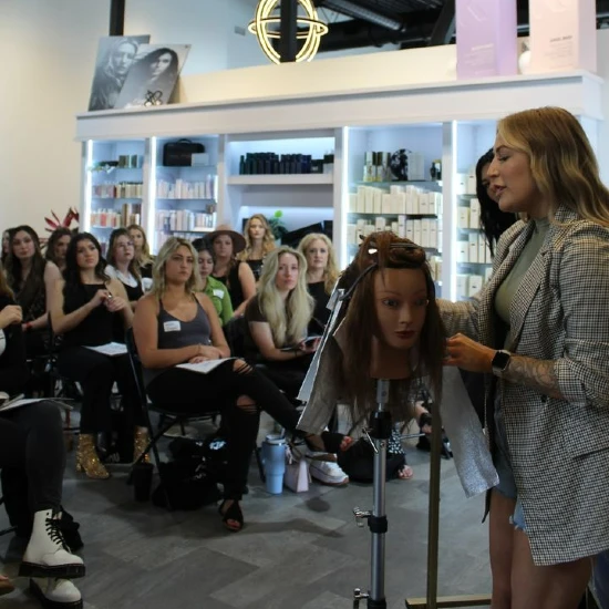 Kaylee Smiley teaching a hair styling class with a mannequin head