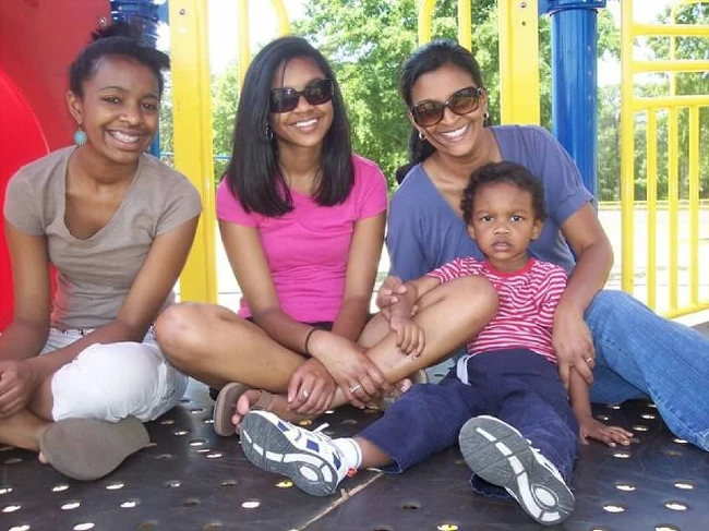 Shelly Ismail sitting on a structure in the playground with her kids