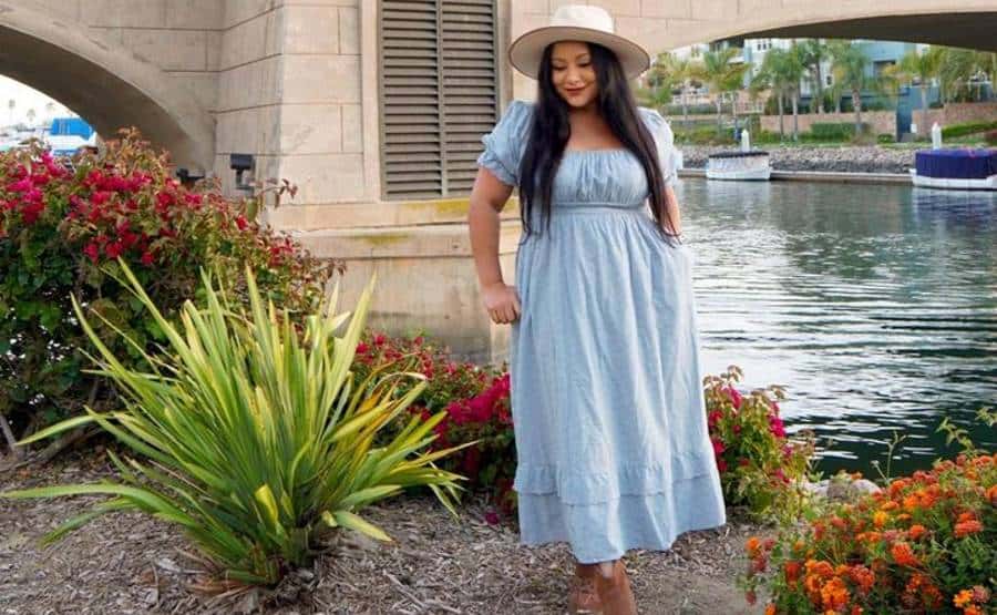 Nelly Salomon blue dress posing by riverside bridge