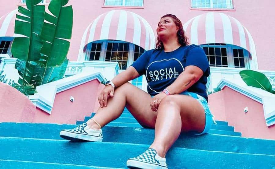 Candace Moore sitting on steps in front of a pink building