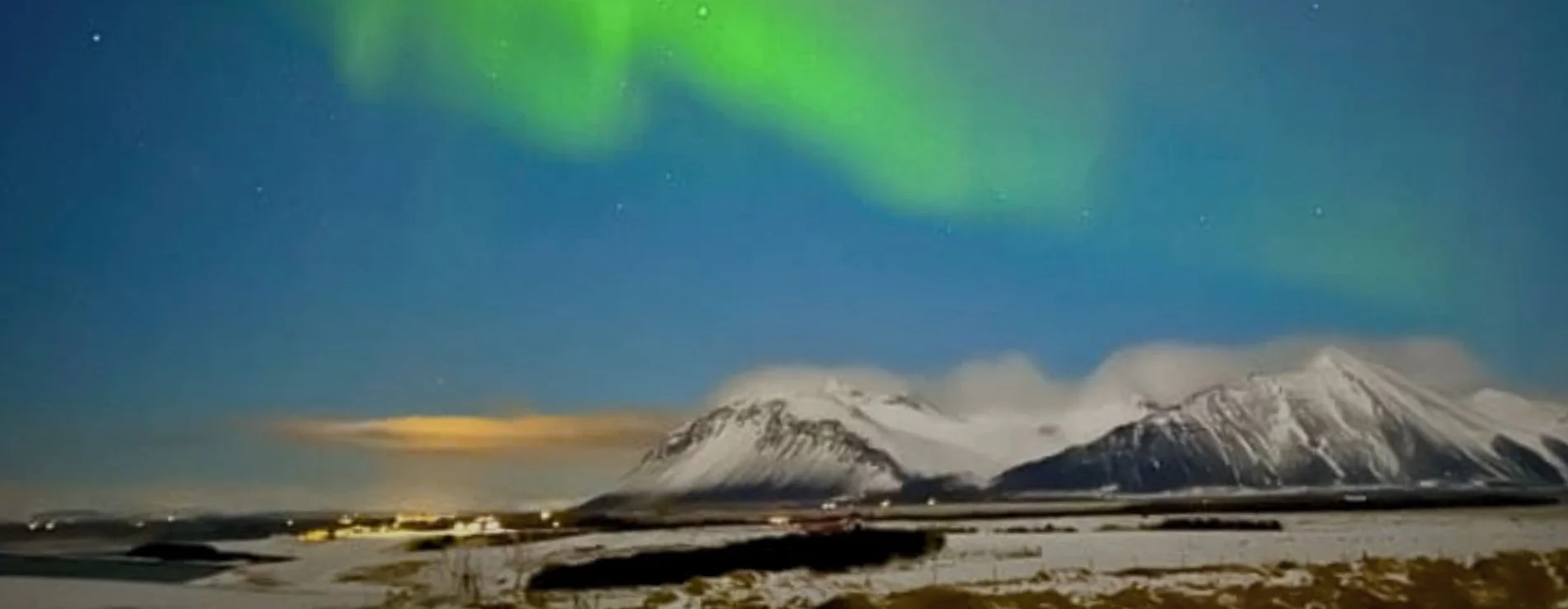 Borgarnes Iceland with Northern Lights above snowy mountains.