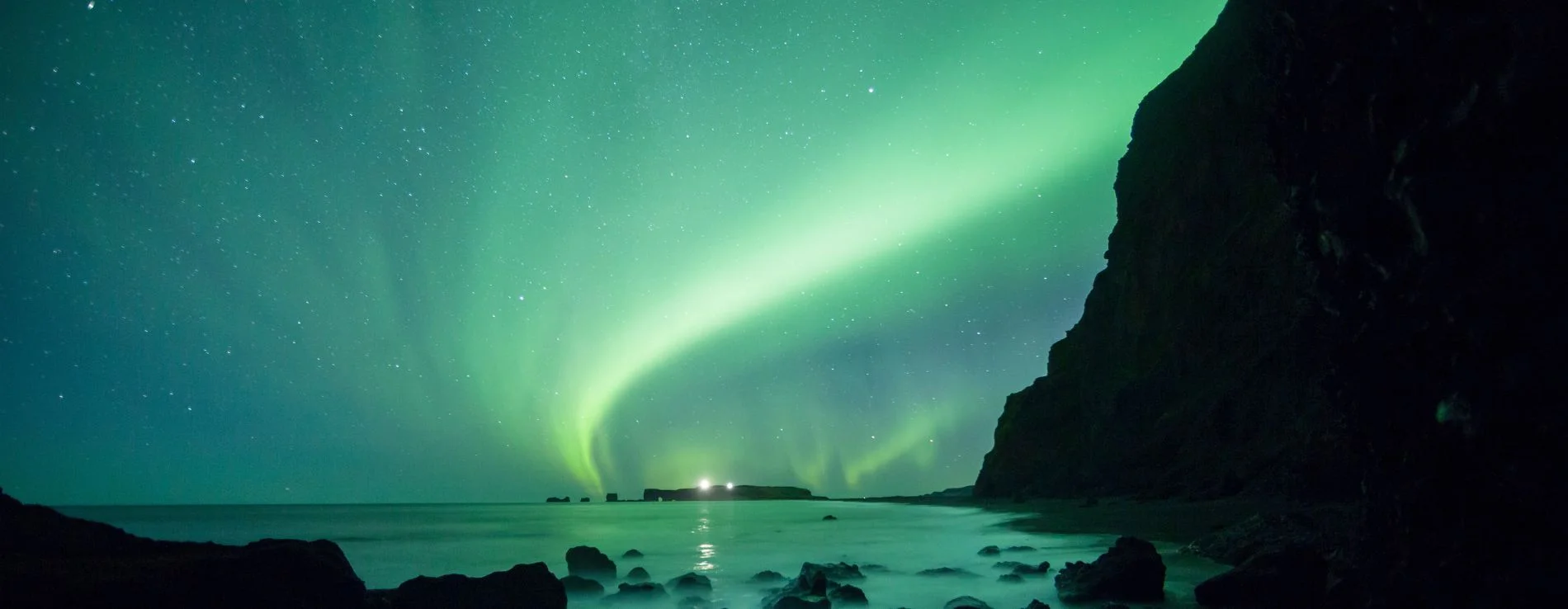 Reynisfjara Black Sand Beach under green Northern Lights in Iceland.