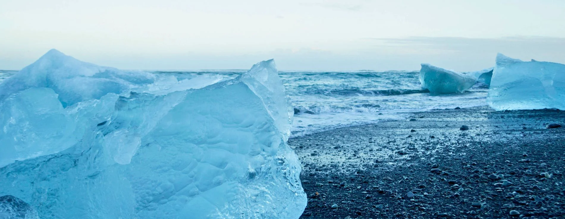 Diamond beach black sand beach in winter with icebergs on the sand and waves coming in.
