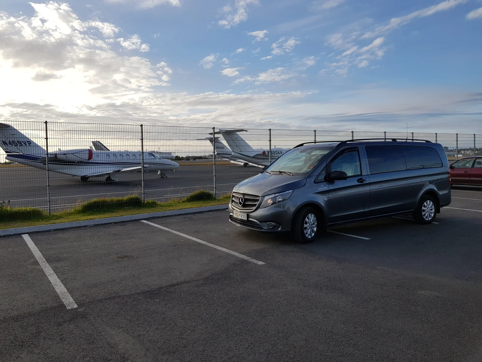 Private Airport Shuttle van outside airport in Iceland with planes in the background.