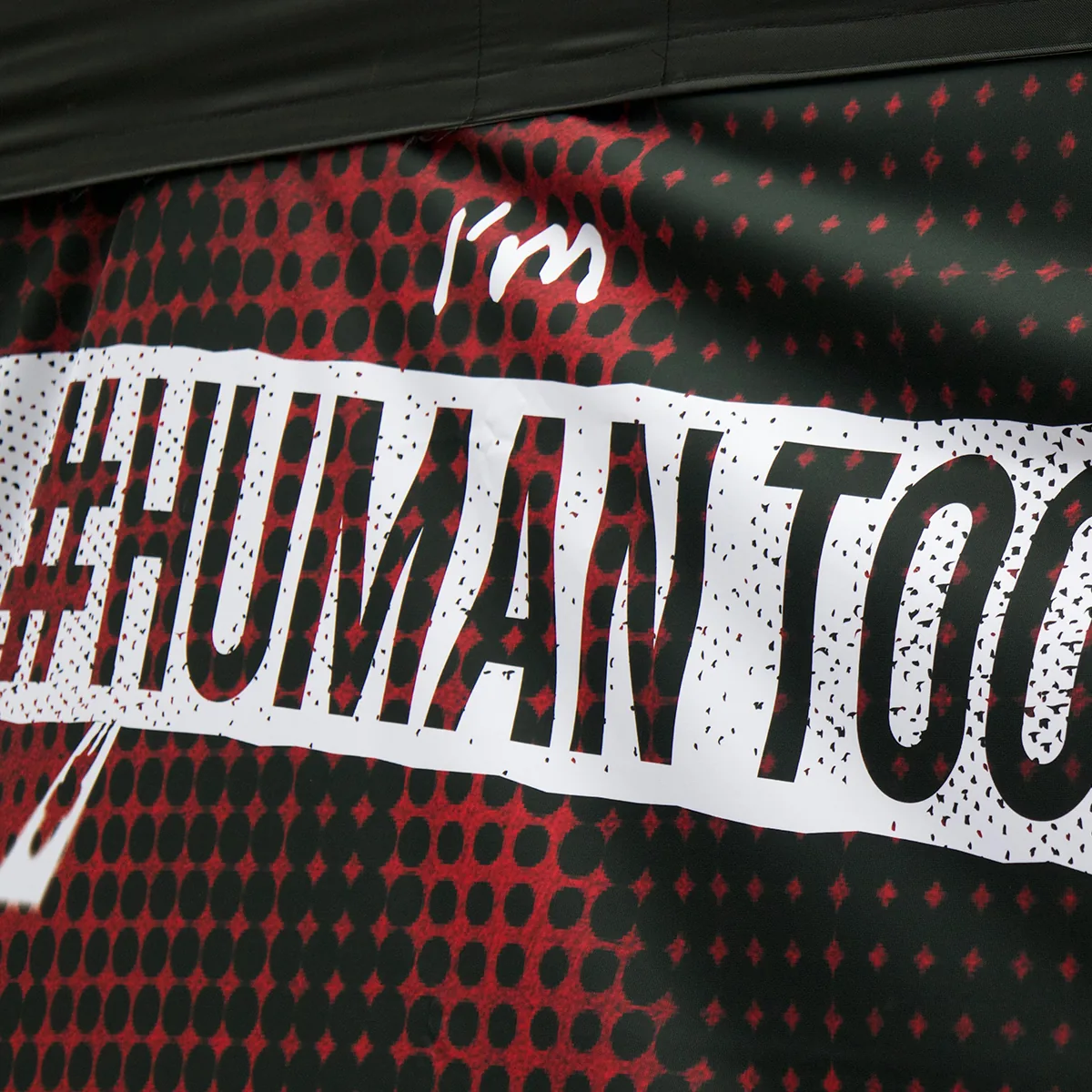 A close-up of the I’m #HUMANTOO graphic in black and white on a red halftone background
