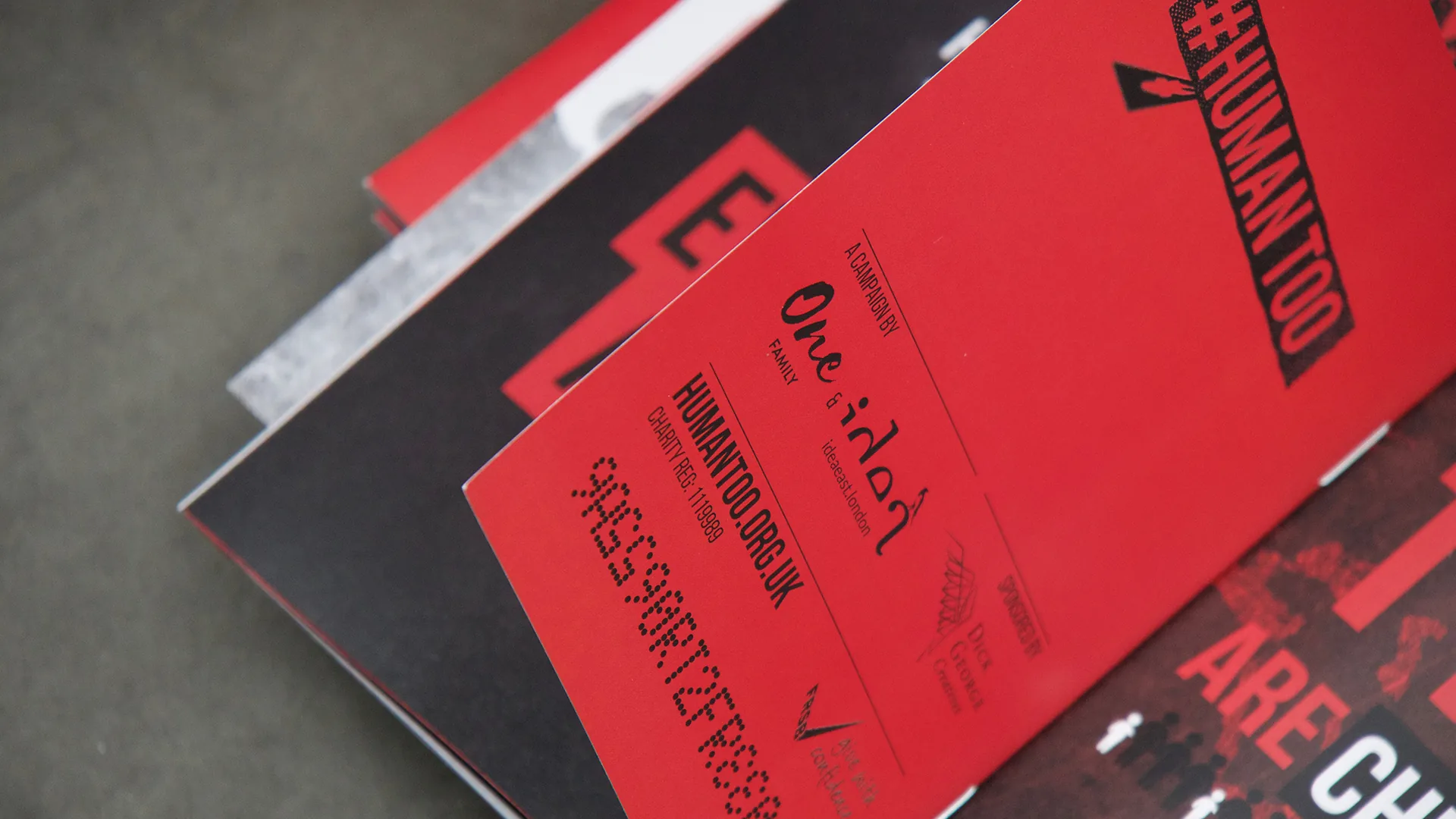 Close-up of the red #HUMANTOO passport with its One Family and humantoo.org.uk details