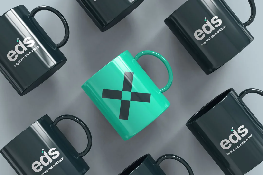 Black EDS mugs around a turquoise mug printed with the X mark