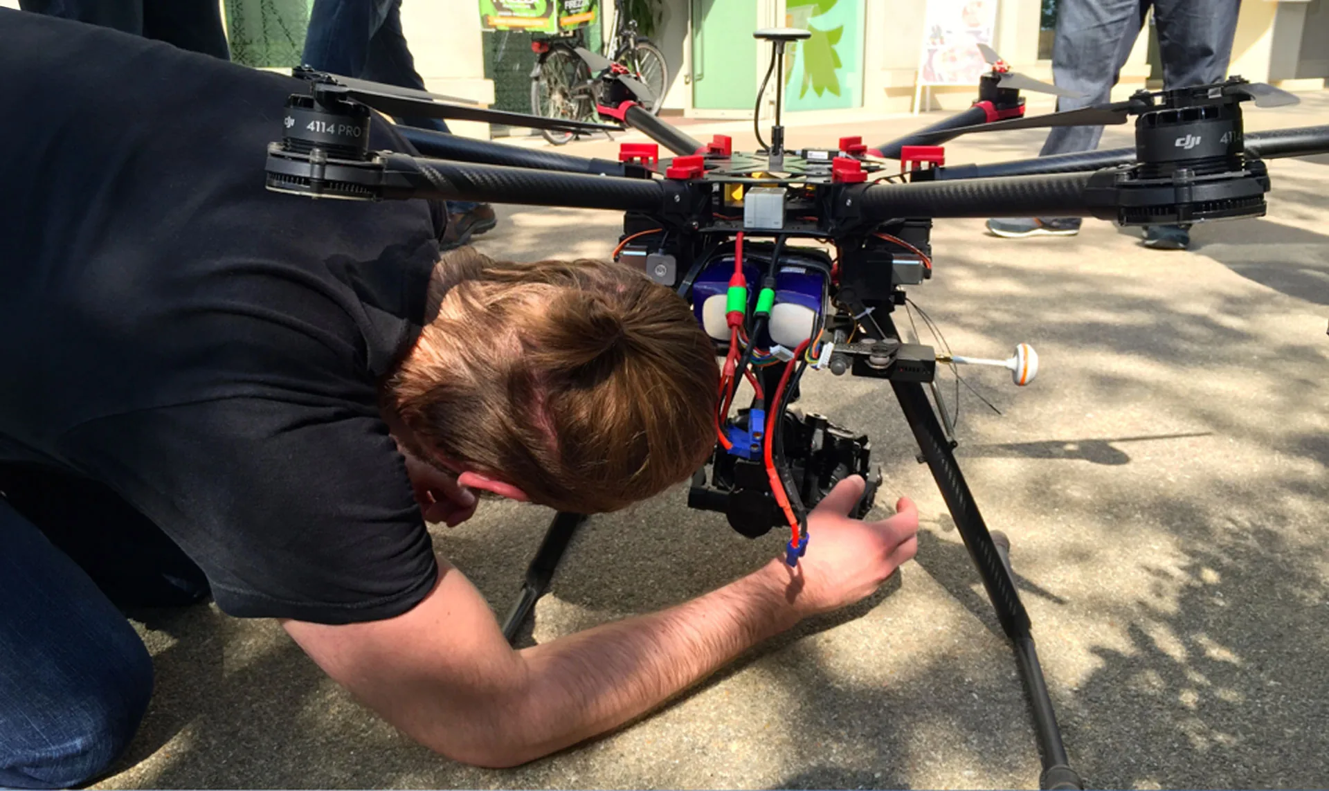 A crew member adjusting a camera rig on a large black drone on a London pavement during the Firezza film shoot