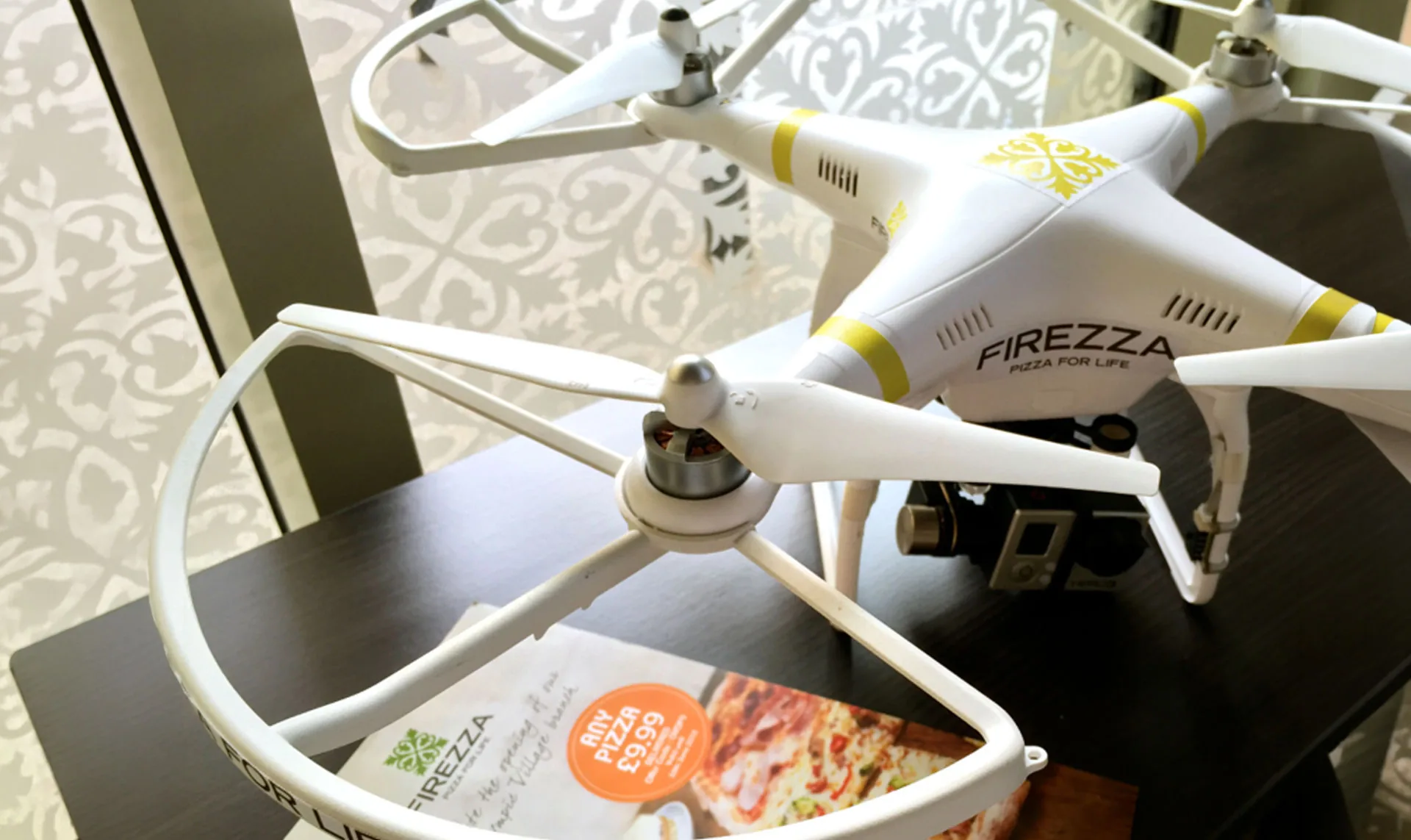 A white Firezza-branded drone resting on a table beside a Firezza menu