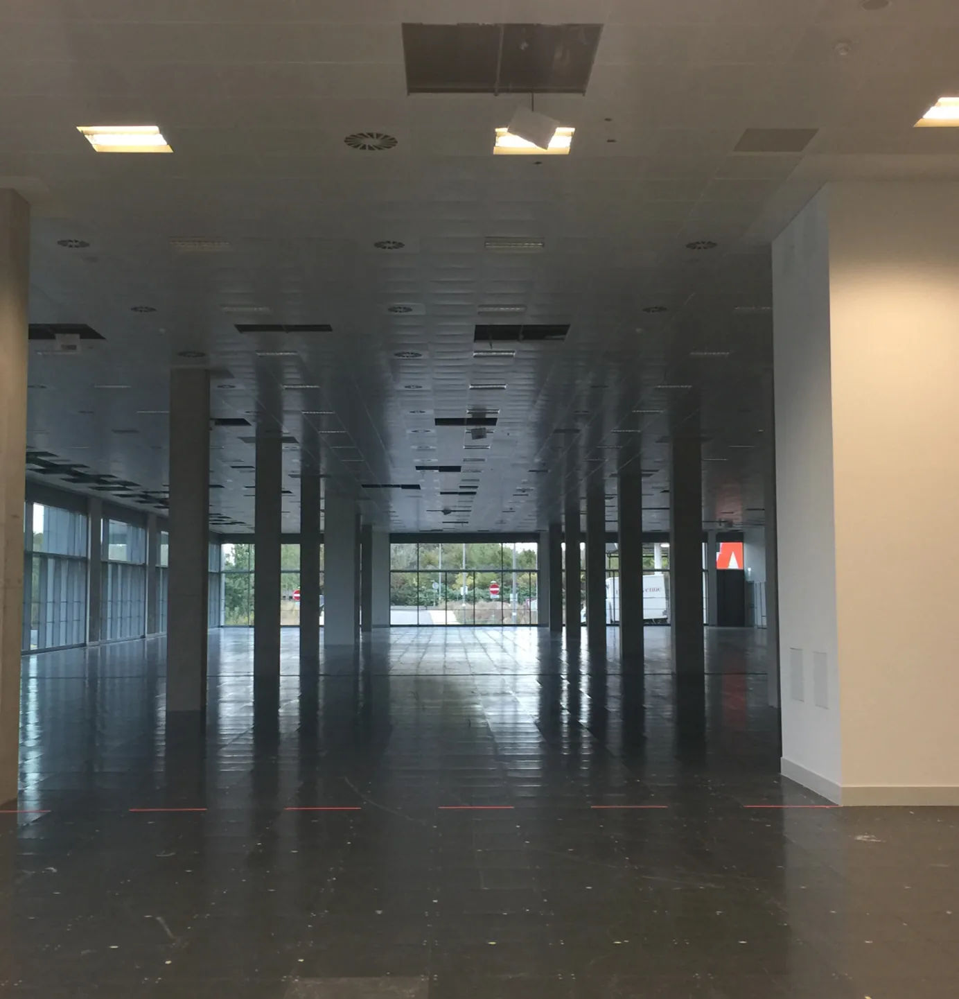 The empty raw shell of the Plexal space before fit-out, with columns and floor-to-ceiling windows