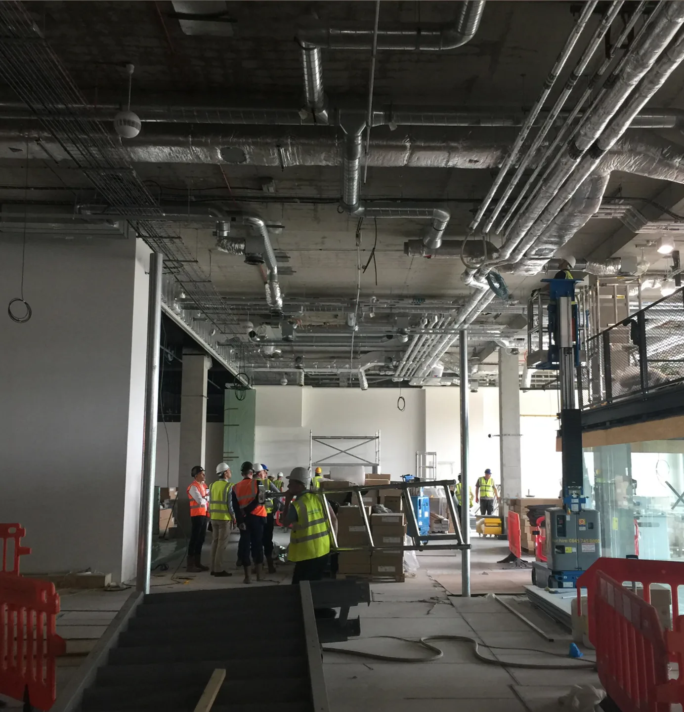 Workers fitting out an industrial interior with exposed ducts during the Plexal build
