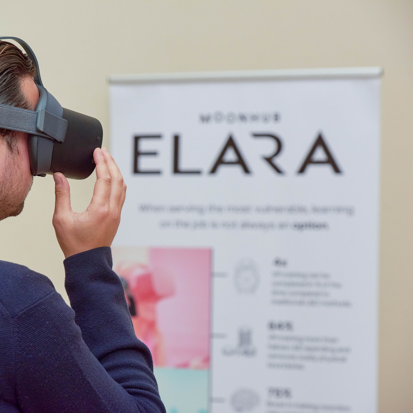 A guest at Moonhub’s dementia care panel event tries a VR headset in front of an Elara banner