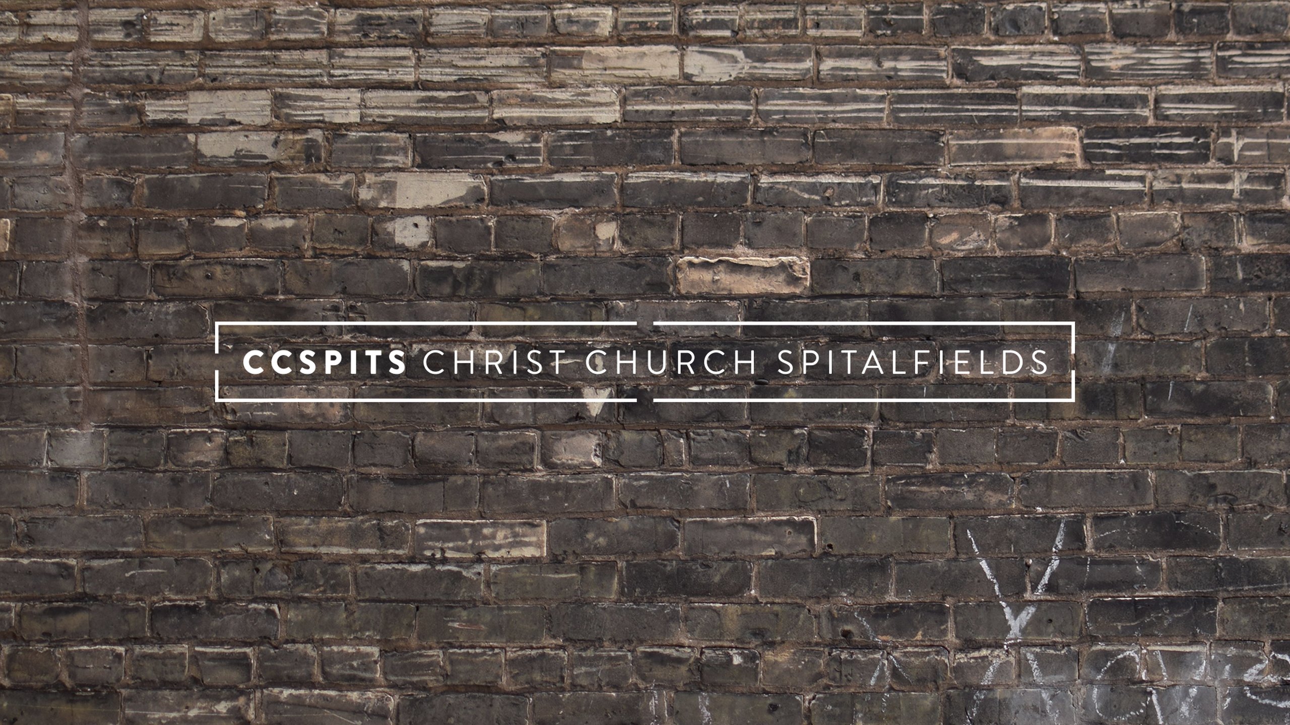The full Christ Church Spitalfields logo in white, the word CCSPITS in bold followed by Christ Church Spitalfields inside a thin bracketed frame, set on a weathered dark brick wall