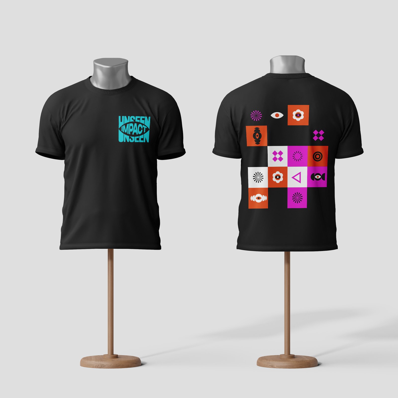 Two black T-shirts on mannequin stands, one with a small cyan UNSEEN IMPACT logo on the chest and one with a grid of coloured icons