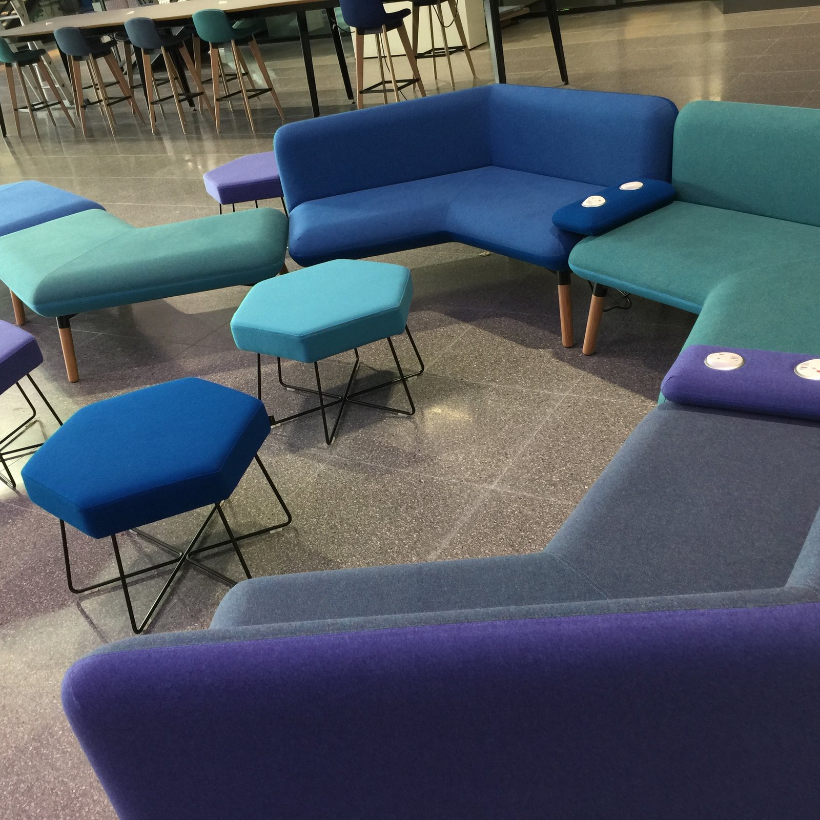 Modular sofas and hexagonal stools in blue, teal and purple in a Plexal lounge