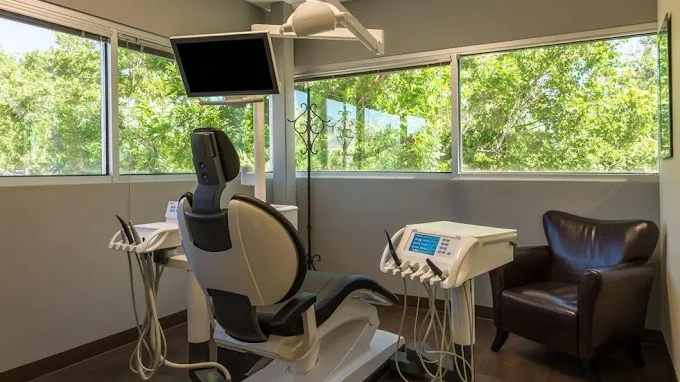 Dental treatment room with patient chair, overhead light, and monitor at Parkway Dental