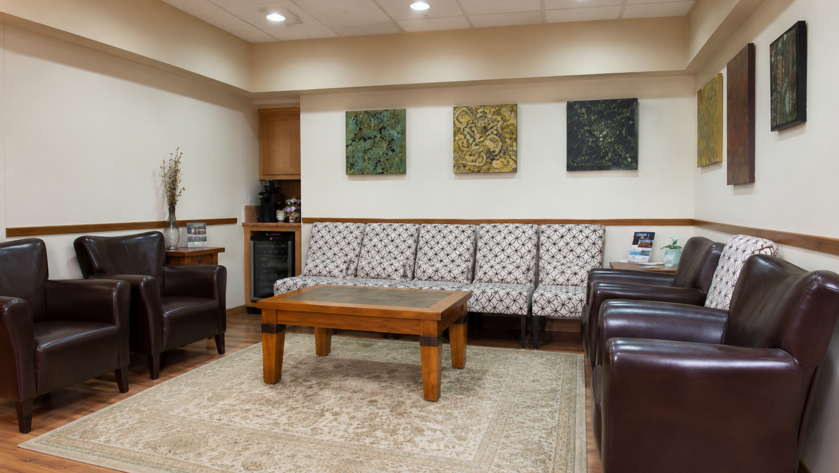 Spacious patient waiting room at Parkway Dental with leather armchairs, patterned sofa, coffee table, beverage station, and wall art