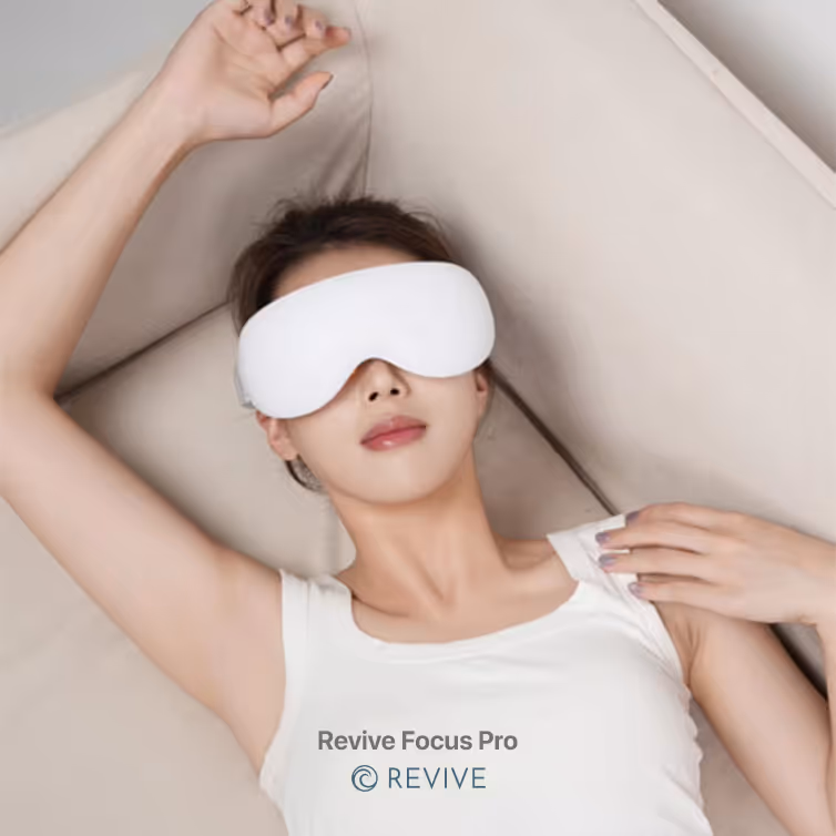 Mujer recostada con venda blanca para ojos Relax mientras descansa en un sofá beige.