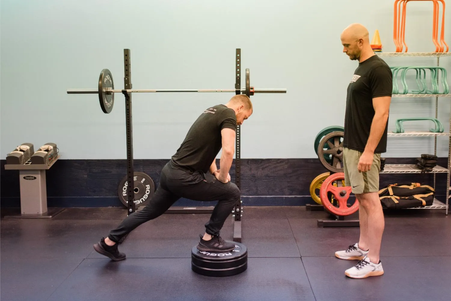 Coach supervising a client's split squat on a plyo box at Top Tier Physical Therapy in Middletown, DE.