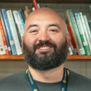 Mr. Jesus Chavez smiling in front of a bookshelf