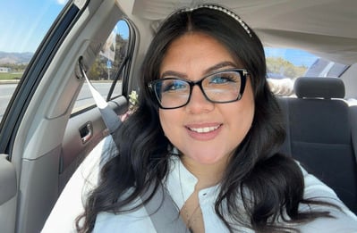 Ms. Mallely De La Cruz smiling in a car wearing glasses