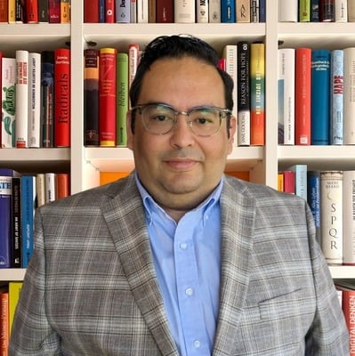 Mr. Victor Argueta faculty member posed before bookshelf