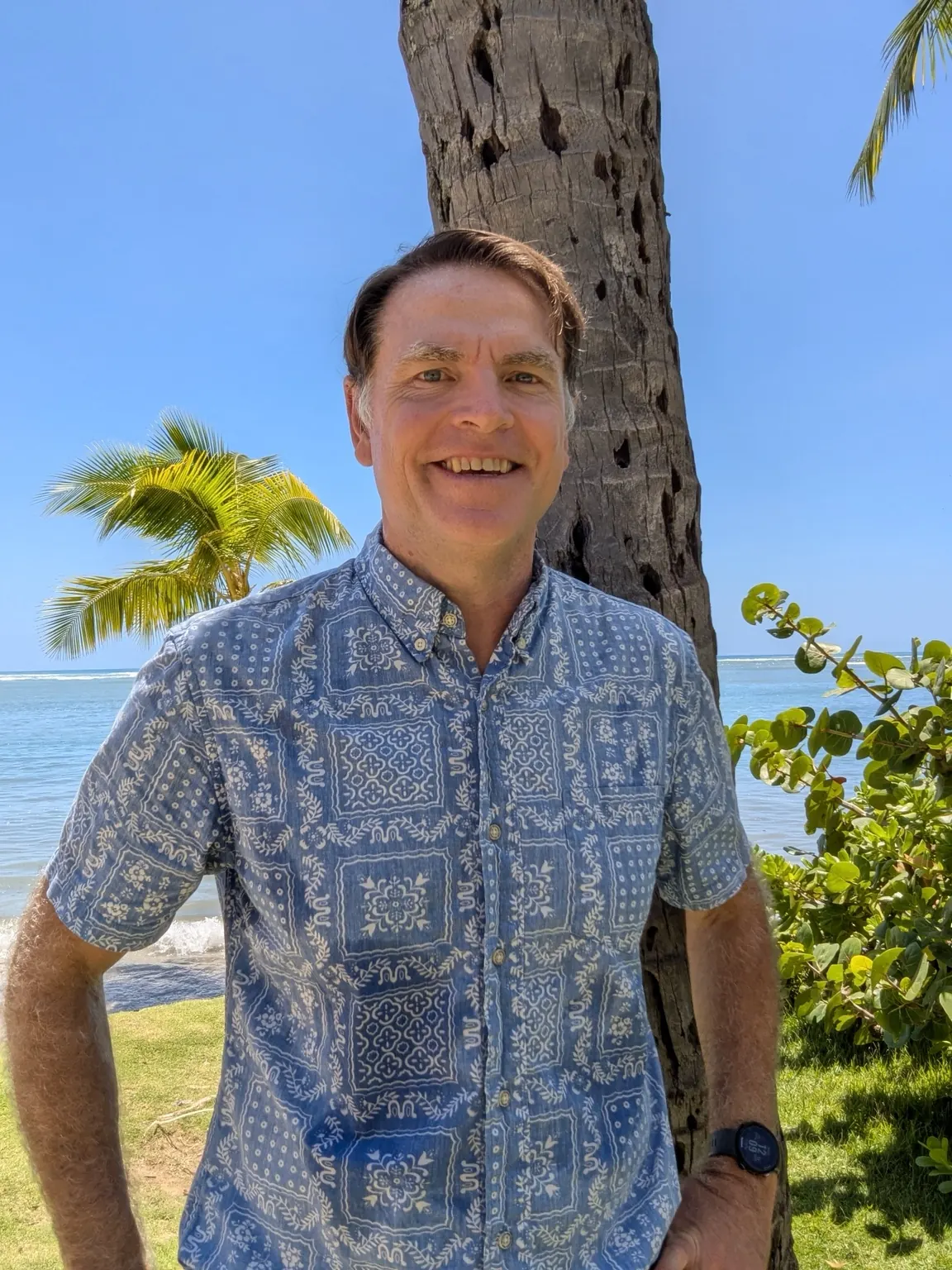 man-smiling-by-palm-tree-at-tropical-beach