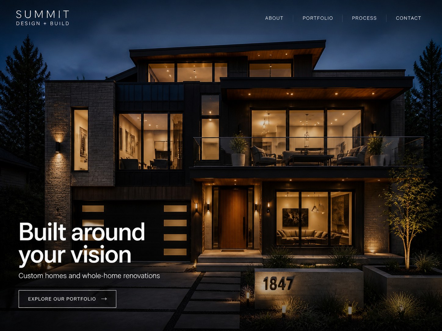 Modern two-story house lit warmly at night with large windows and a balcony above the entrance.