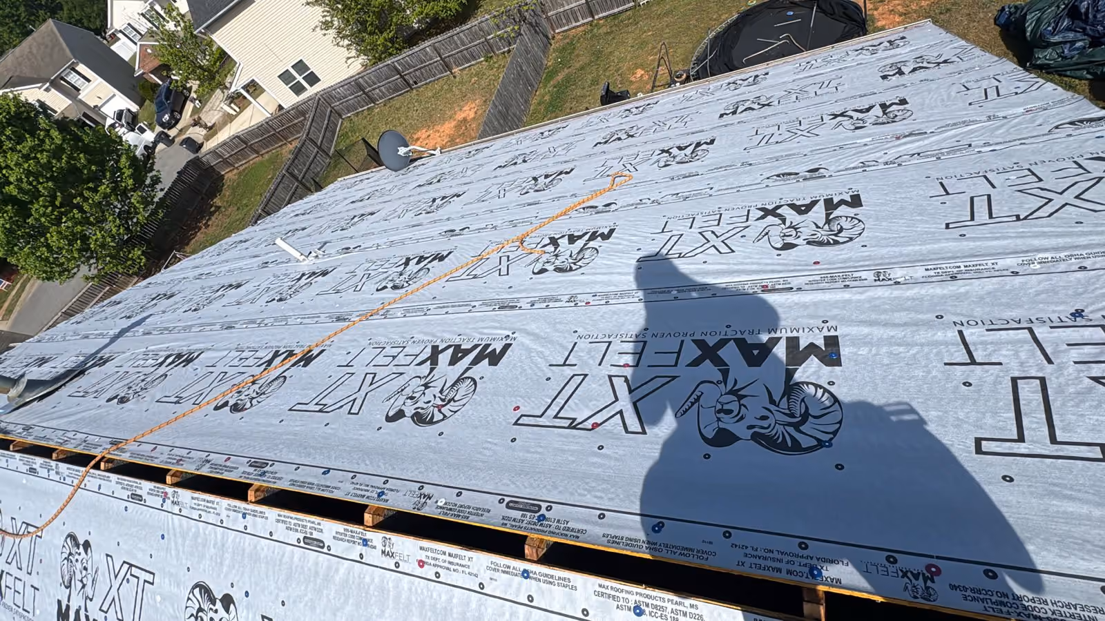 Roof under construction covered with MaxFelt XT roofing underlayment and an orange rope across it.