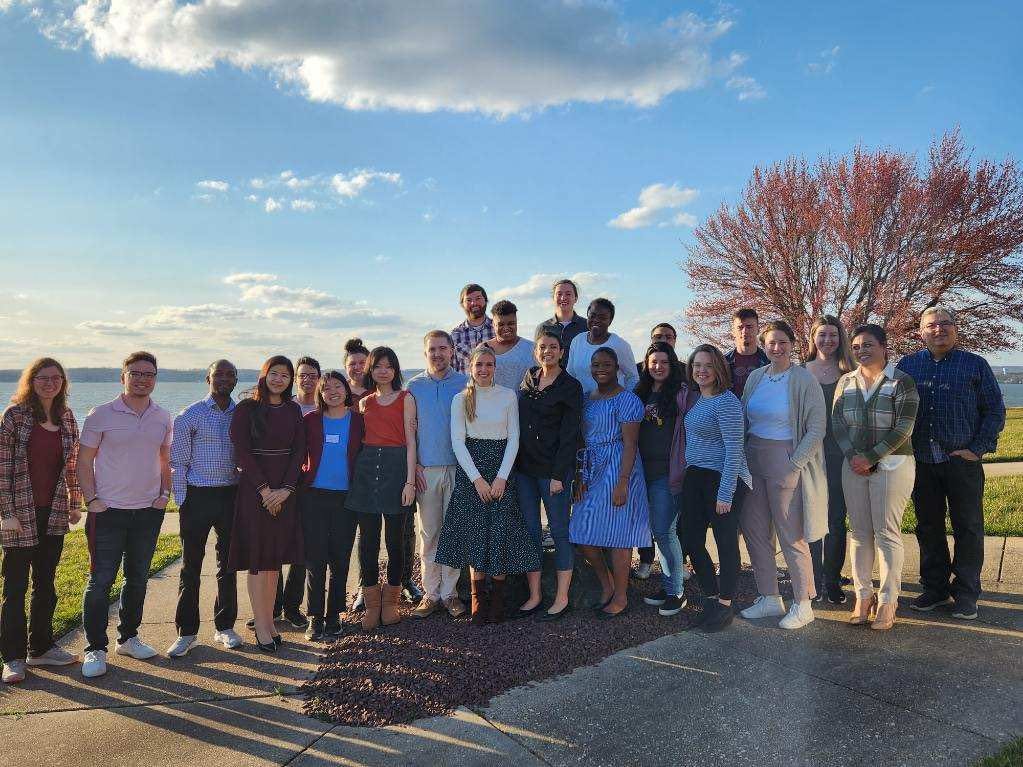 Young adults gathered together outdoors by the water at the Fan Into Flame retreat