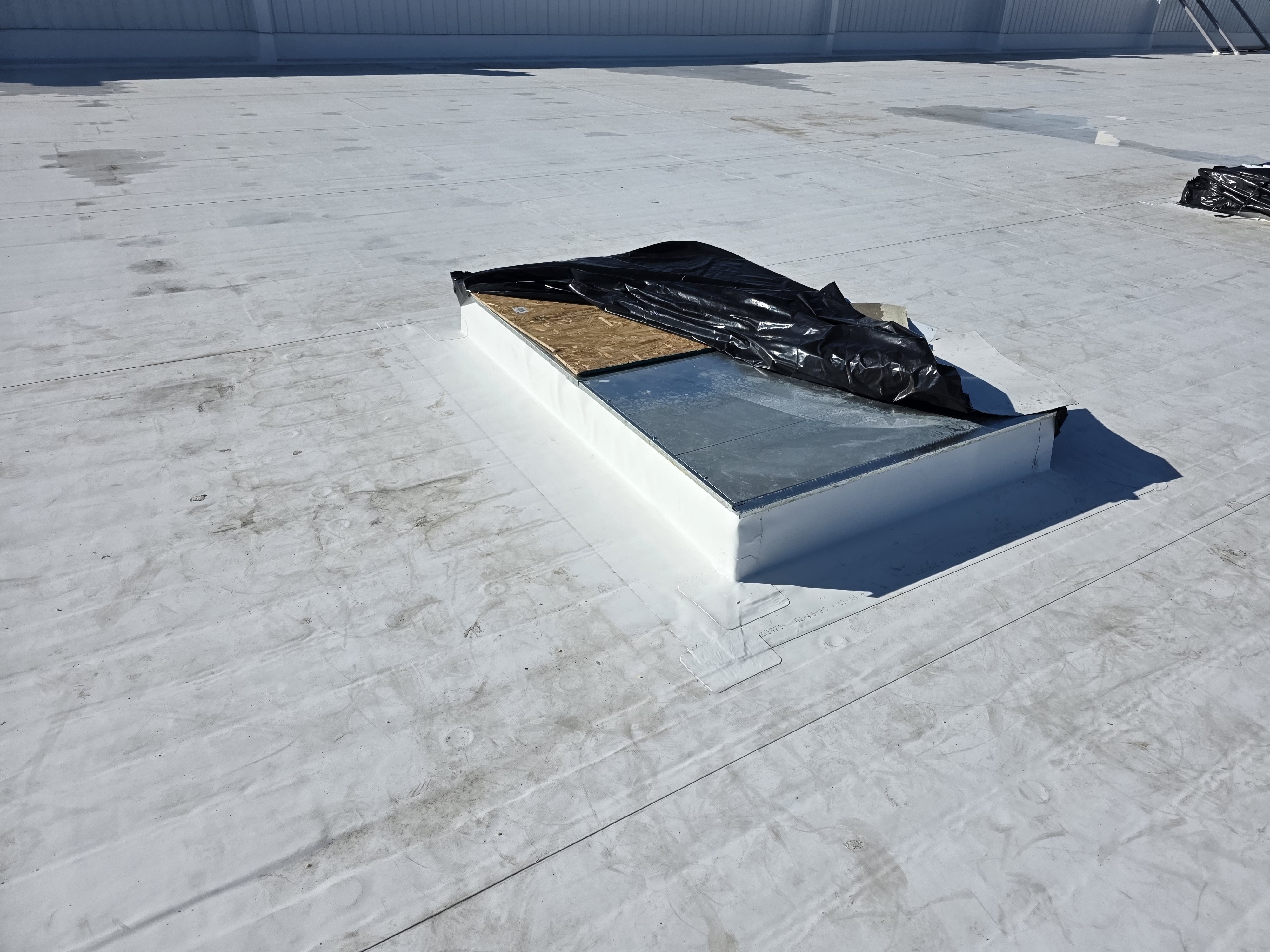Rooftop skylight curb being prepped for sealing