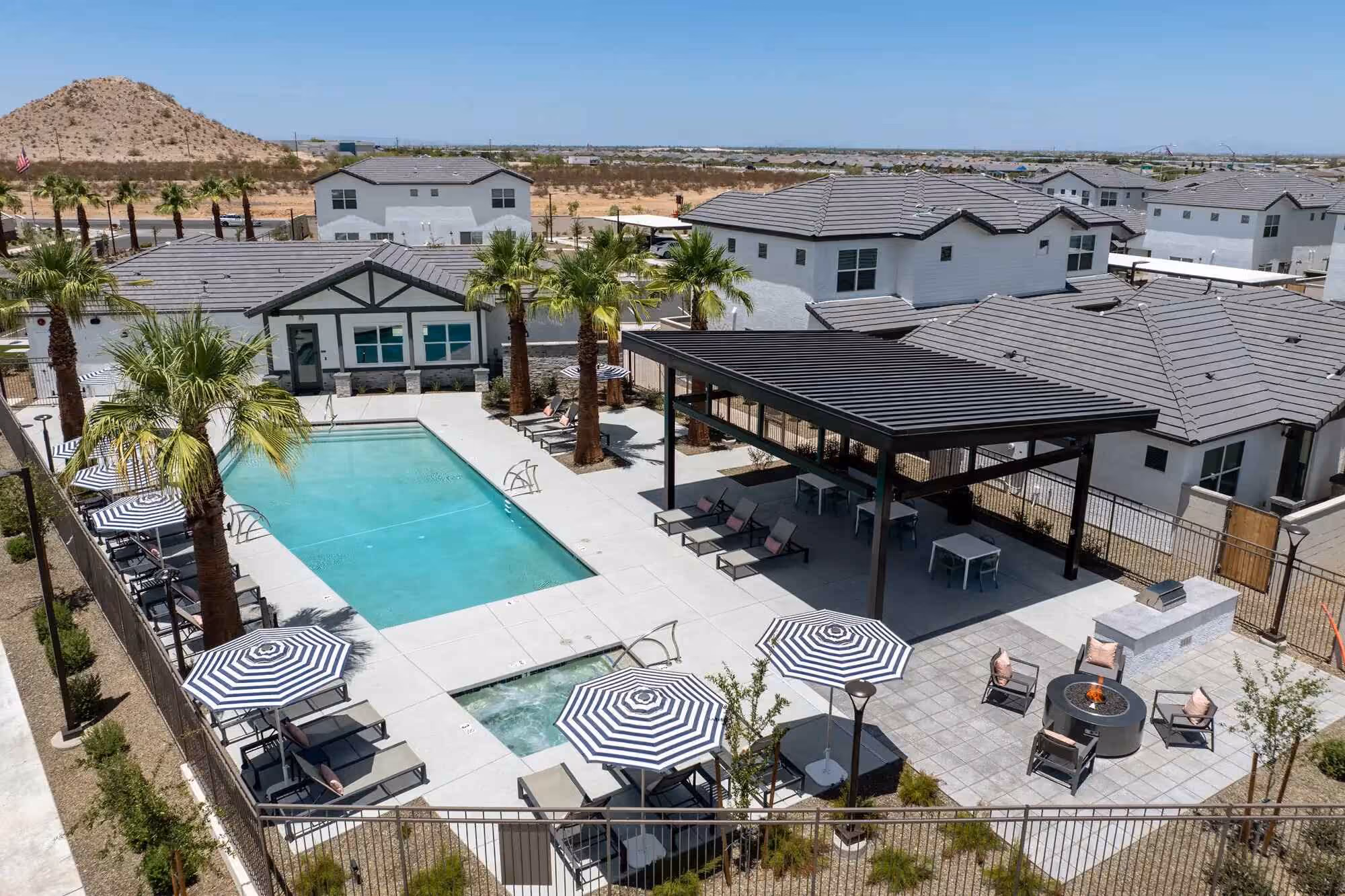 Birds eye view of Pique Residences pool area with palm trees, cabana, and lounge chairs with umbrellas