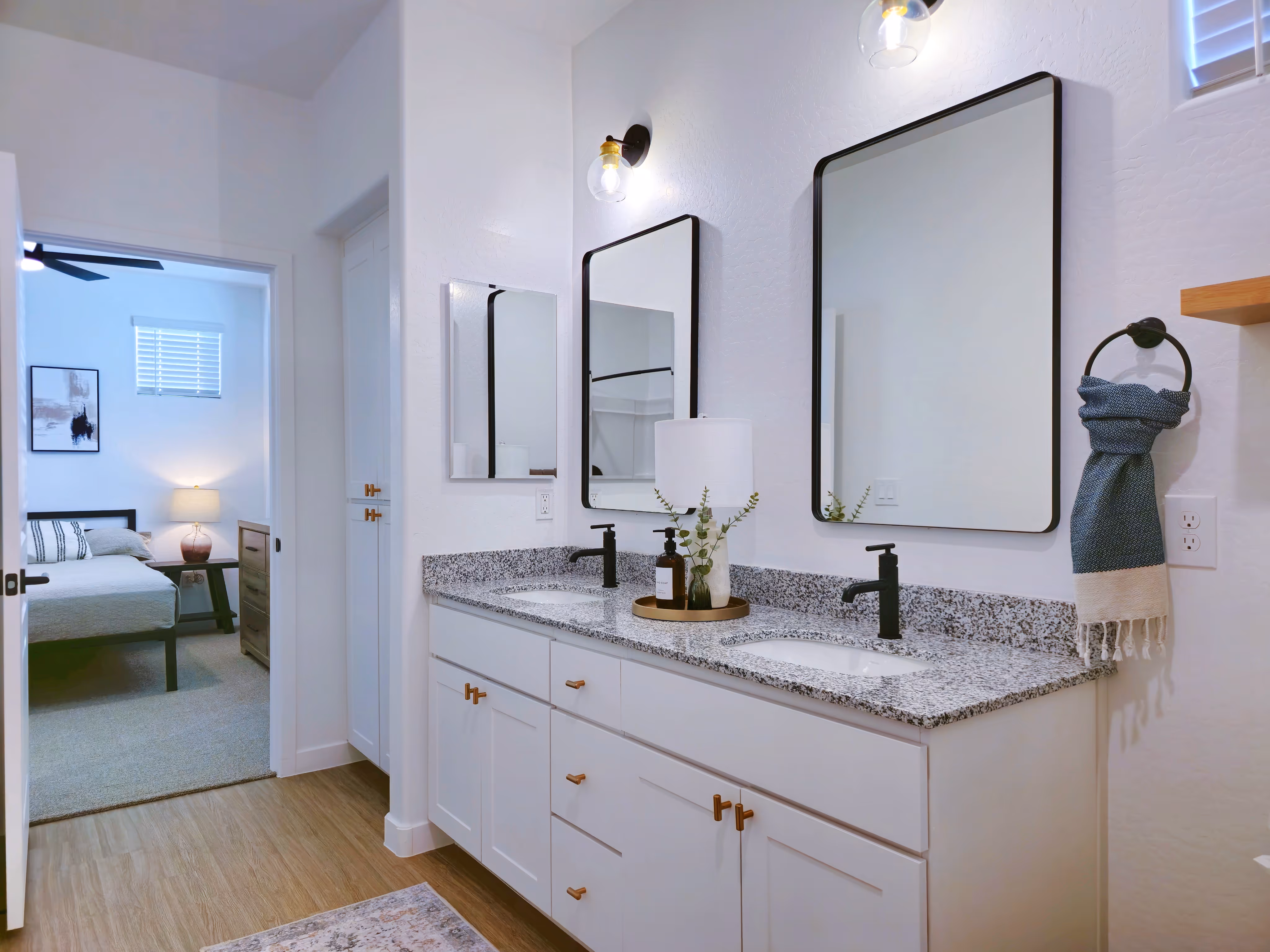 Bathroom with white cabinets and vanity looking into bedroom