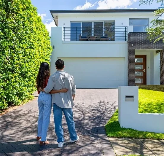 Couple standing in front of their first house after insurance certification
