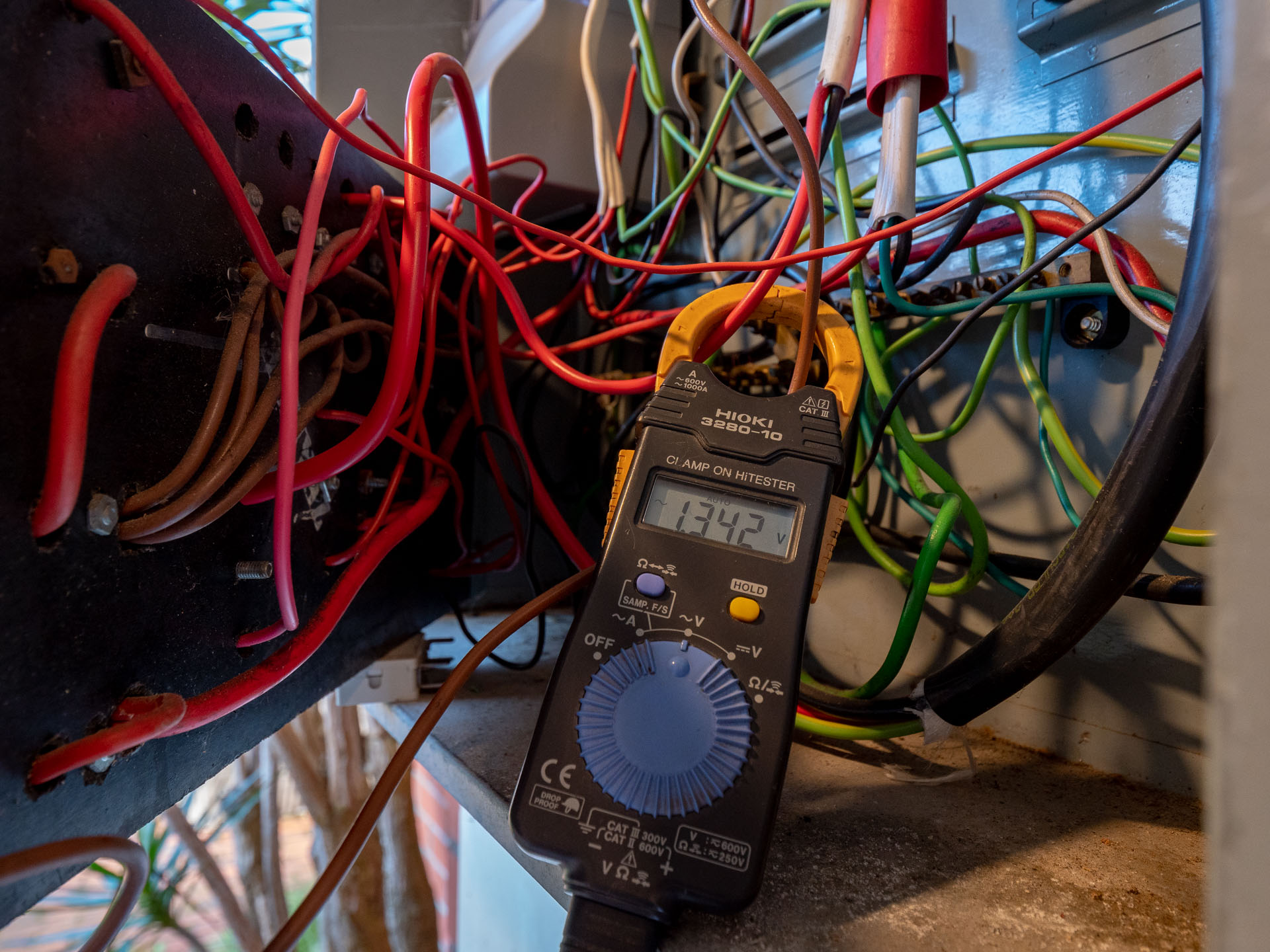 Old tangled wiring being tested with a clamp meter by eCertify