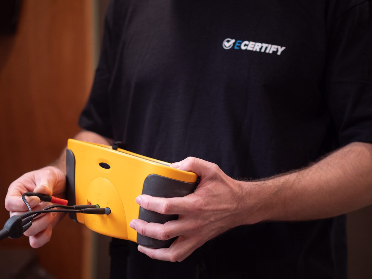 An eCertify electrician holding a test instrument