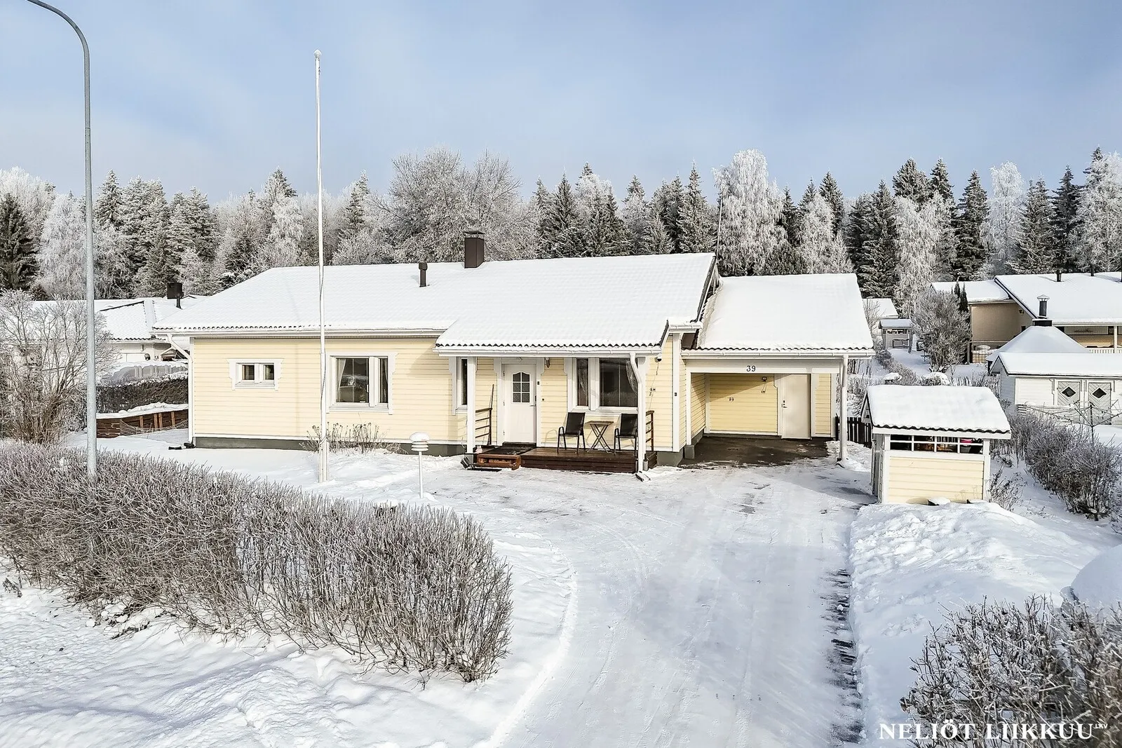 Keltainen omakotitalo lumisessa pihapiirissä talvipäivänä Lahdessa.