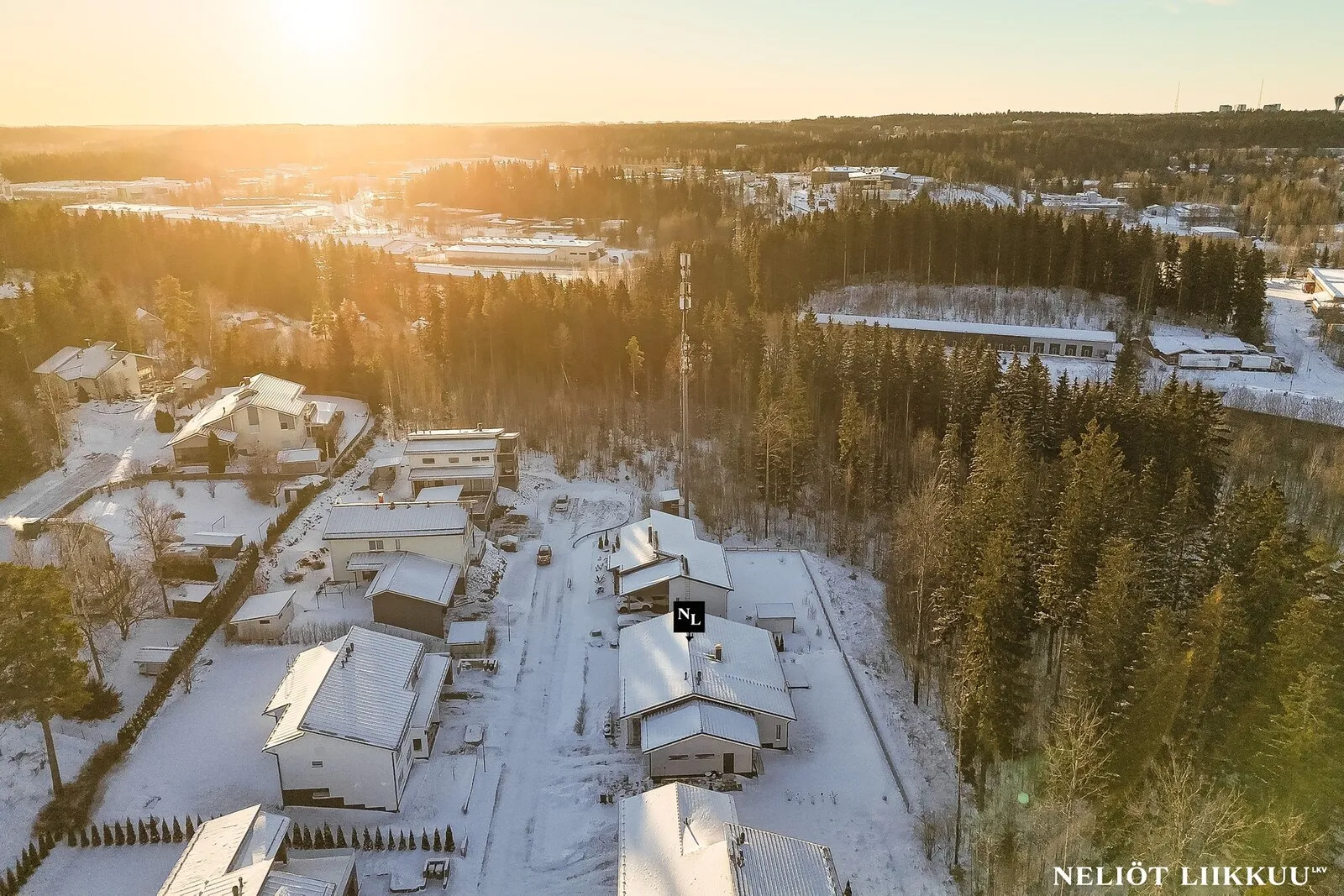 Ilmakuva talvisesta asuinalueesta ja lumisista omakotitaloista auringonlaskun aikaan Lahdessa.