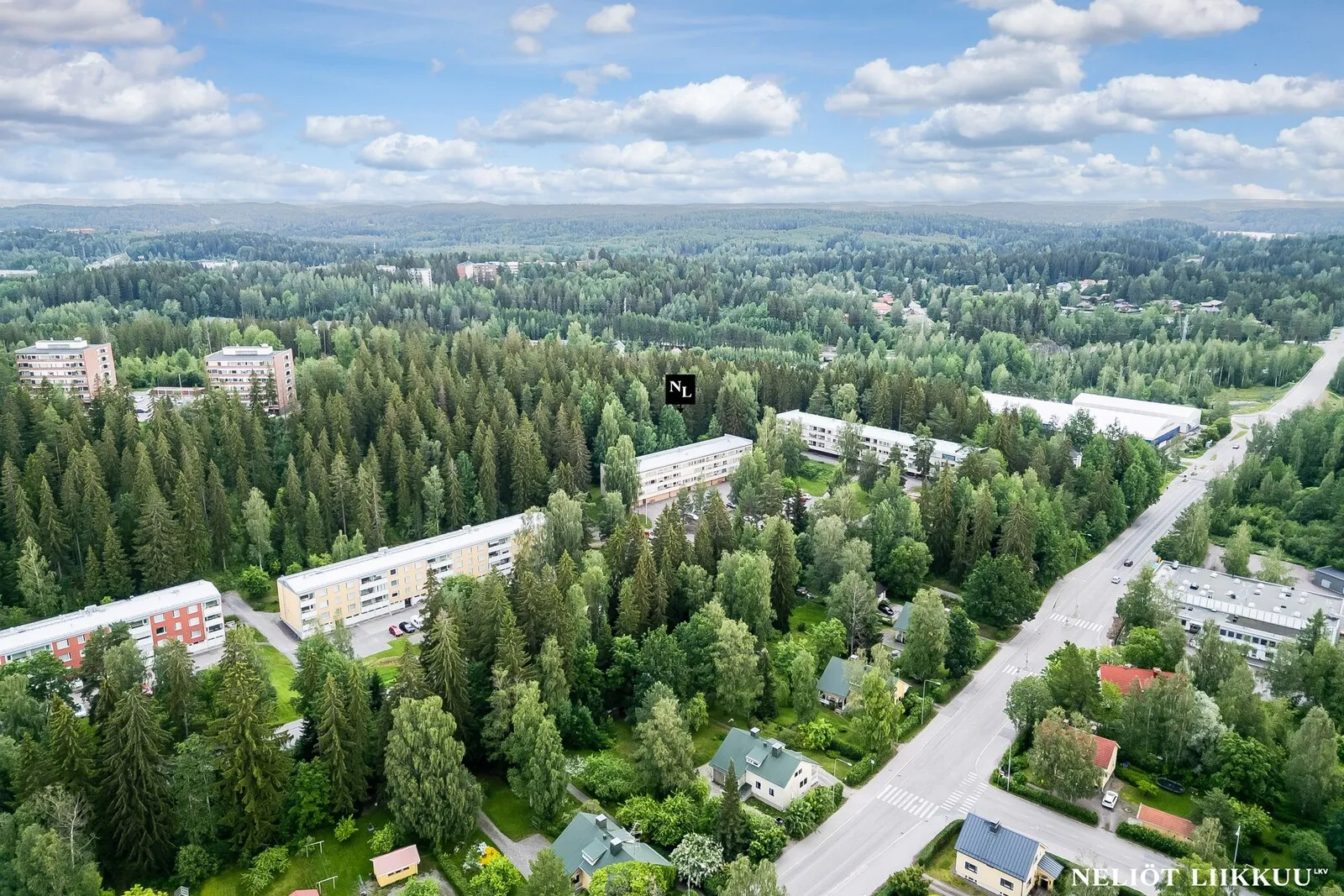Korkea ilmakuva Lahden kerrostaloalueesta, jota ympäröivät laajat metsät ja viheralueet.