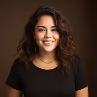 Smiling young woman with curly dark hair wearing a black shirt against a brown background.