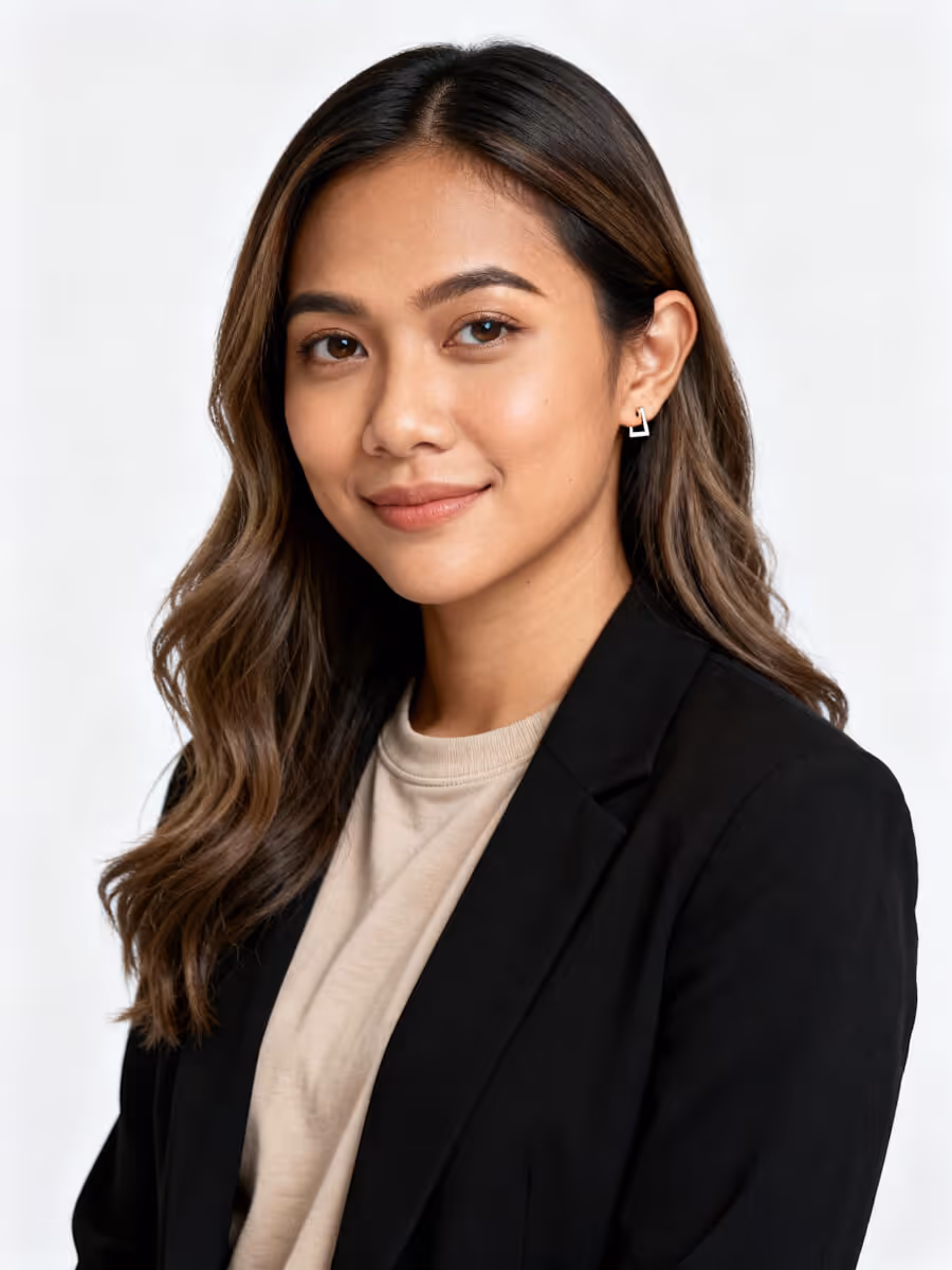 Portrait of a woman with wavy hair wearing a black blazer and beige top, smiling softly.