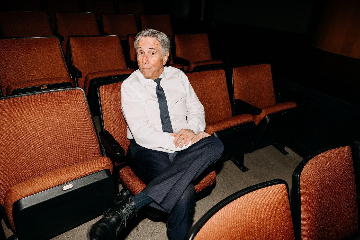 Bernie Smilovitz raising his eyebrows with a playful expression in theater seats