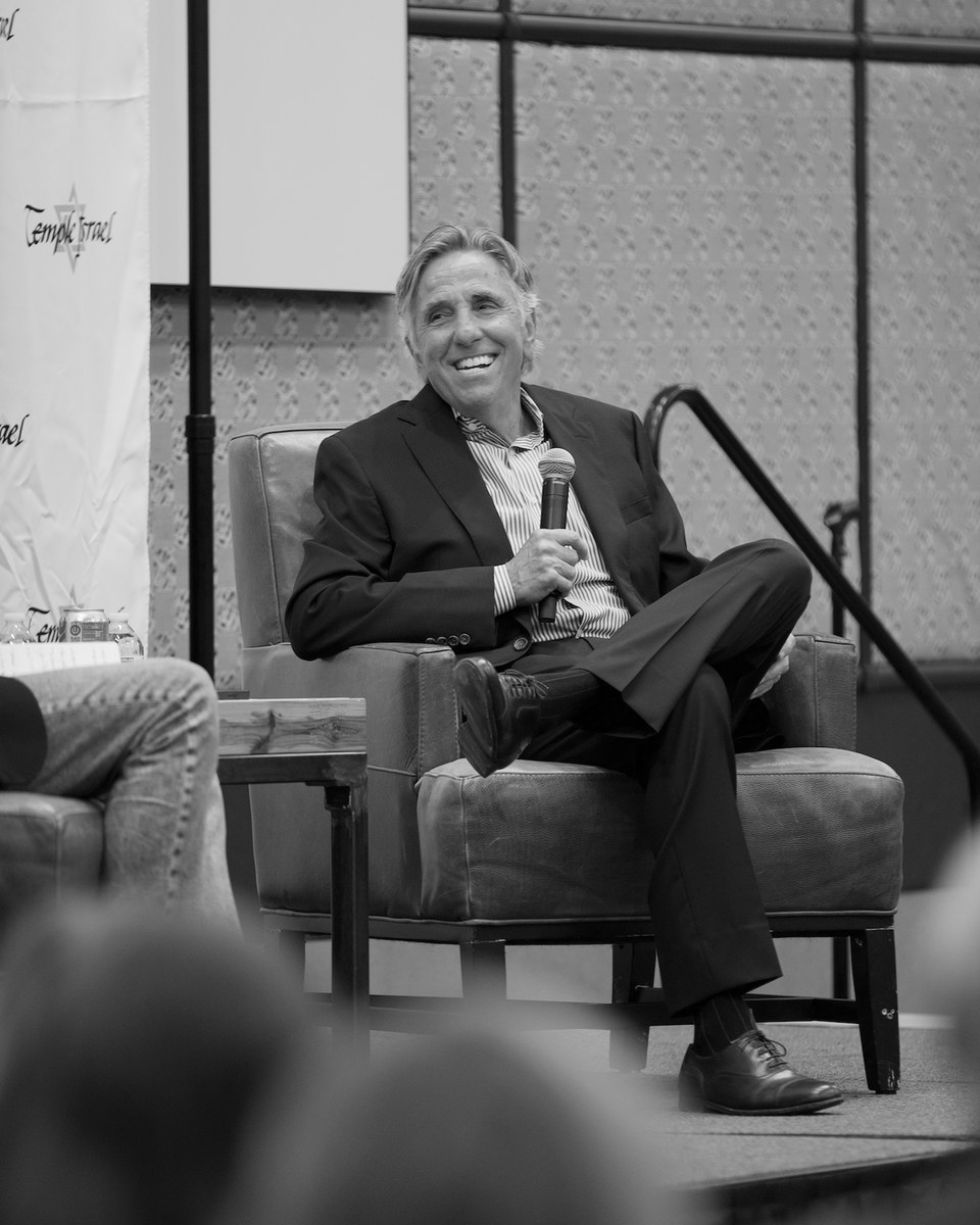 Bernie Smilovitz laughing on stage with a microphone at a live event