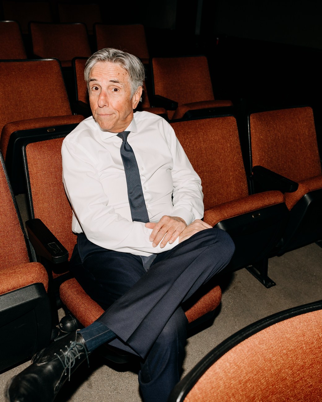 Bernie Smilovitz with a playful, quizzical expression seated in theater seats
