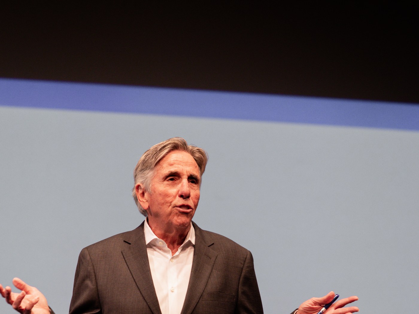 Bernie Smilovitz gesturing with open arms while speaking on stage